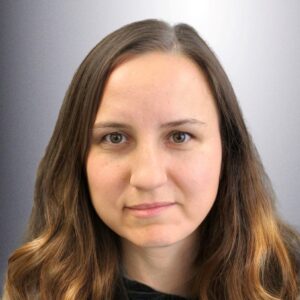 Elena smiling in front of a grey background