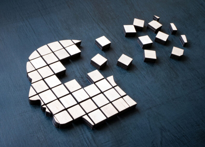 Tiles on a surface come together to make the shape of a human head. Tiles on the back of the head have been moved out of place so that they're outside of the head shape's boundary.