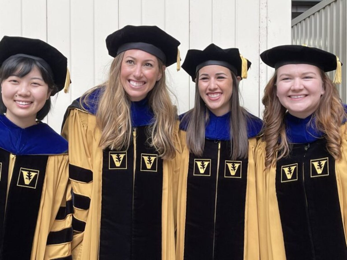 A group of smiling PhD graduates in Hearing and Speech Sciences from VUSM wearing caps and gowns.