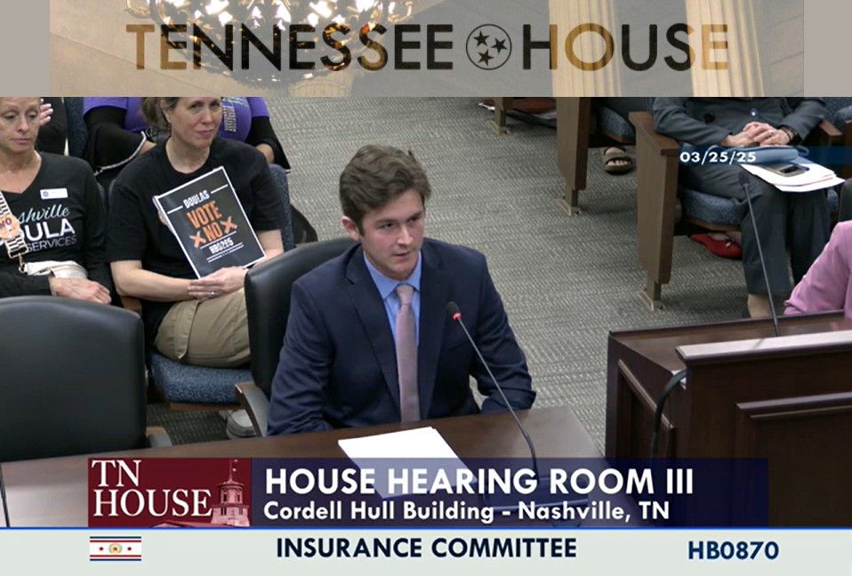 Brian DuVal speaks into a microphone on a dask.