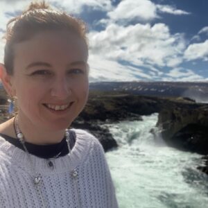 Woman standing in front of ocean shore smiling