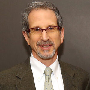 Walter in a suit and tie smiling with a grey background