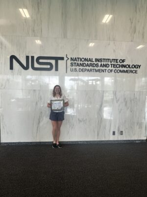 Chloe Whalen in front of the NIST sign.