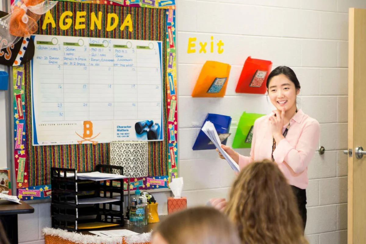 A woman is standing in front of a classroom.