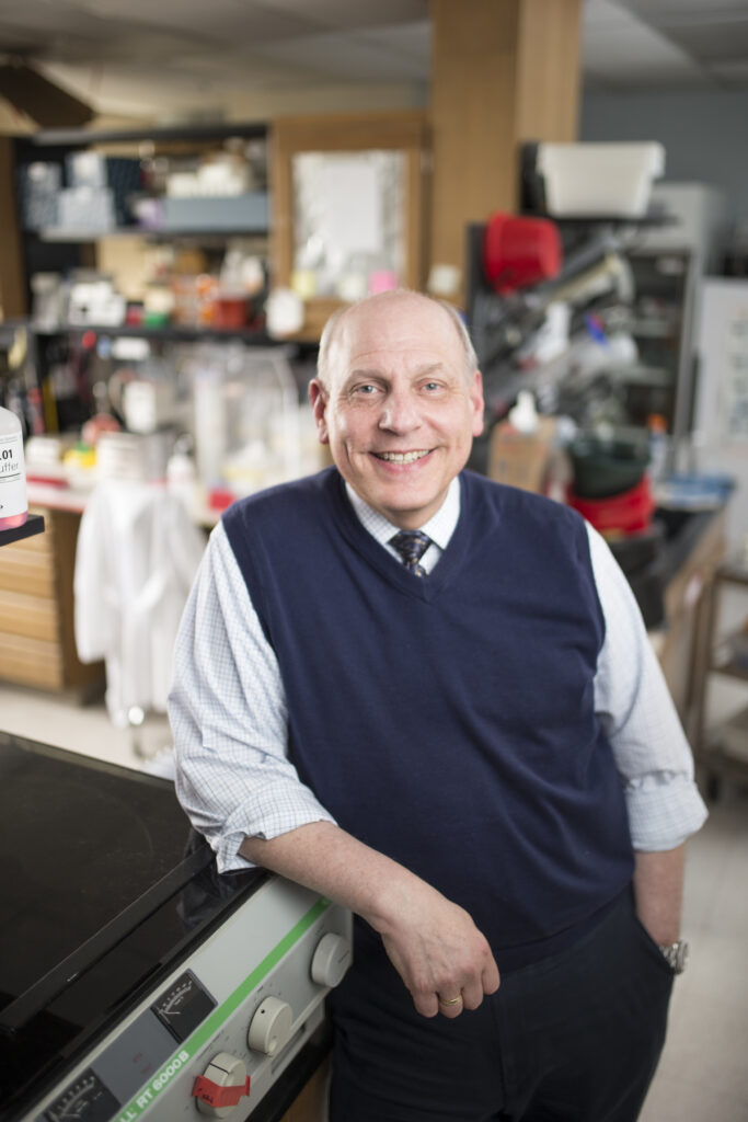 Neil Osheroff leaning against a centrifuge in his lab.