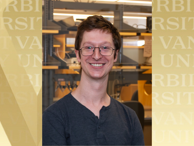 Headshot of Benjamin Brown. He's in front of a glass window. You can see a lab bench and shelves behind him. A gold background flanks the image.