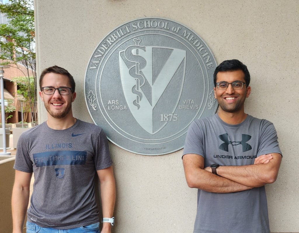 Andrew Rice, left, and Mayuresh Gadgil standing in front of the Vanderbilt School of Medicine seal in front of Light Hall. The photo shows them from the waist up.