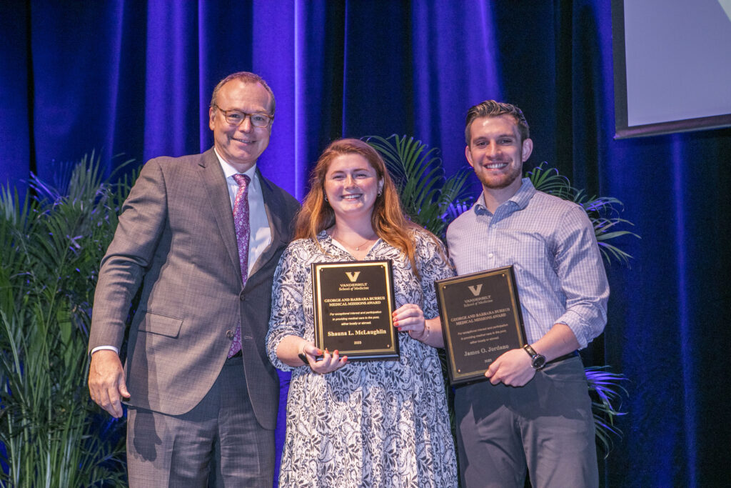 Two award winners stand with a dean
