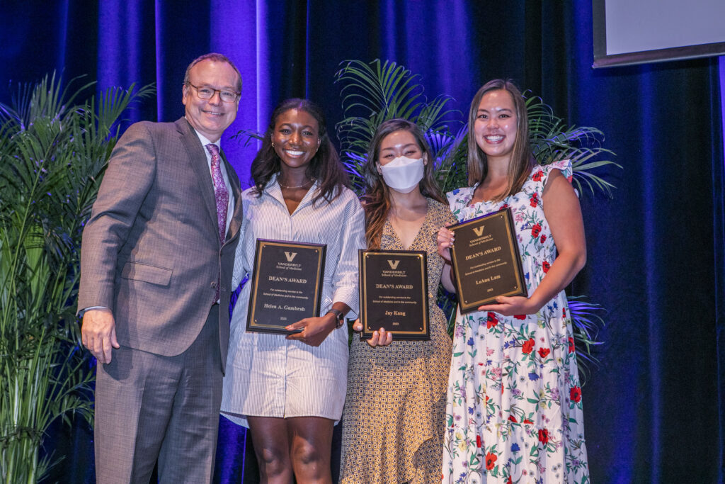 A dean stands with three award winners