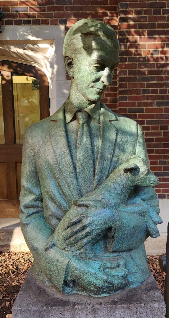 Bronze statue of Virgil LeQuire lovingly holding a baby goat in his arms.