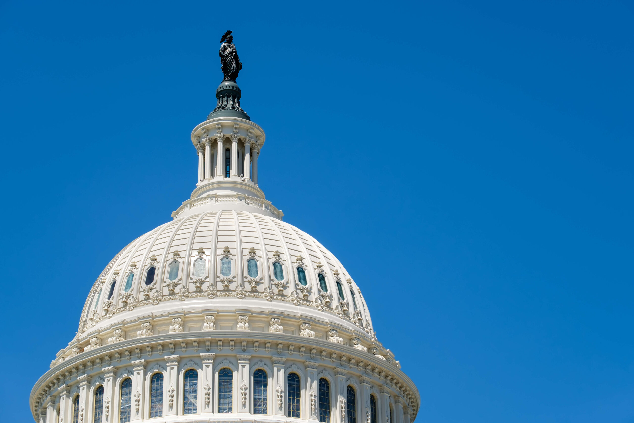 Close-up of the U.S. Capitol dome with the Statue of Freedom against a clear blue sky.