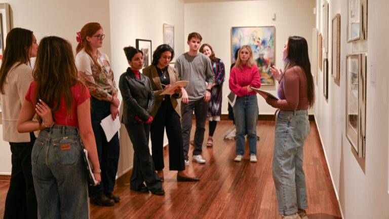 students in an art gallery one presenting to the group