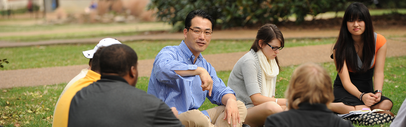 Jeong-Oh Kim teaches Intro to Poetry sitting with students on Library Lawn