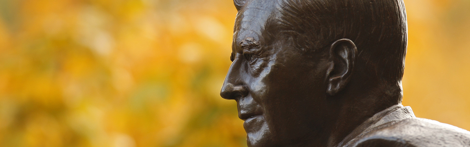 closeup of a statue of Harold Stirling Vanderbilt with trees in the background, located on the Vanderbilt campus