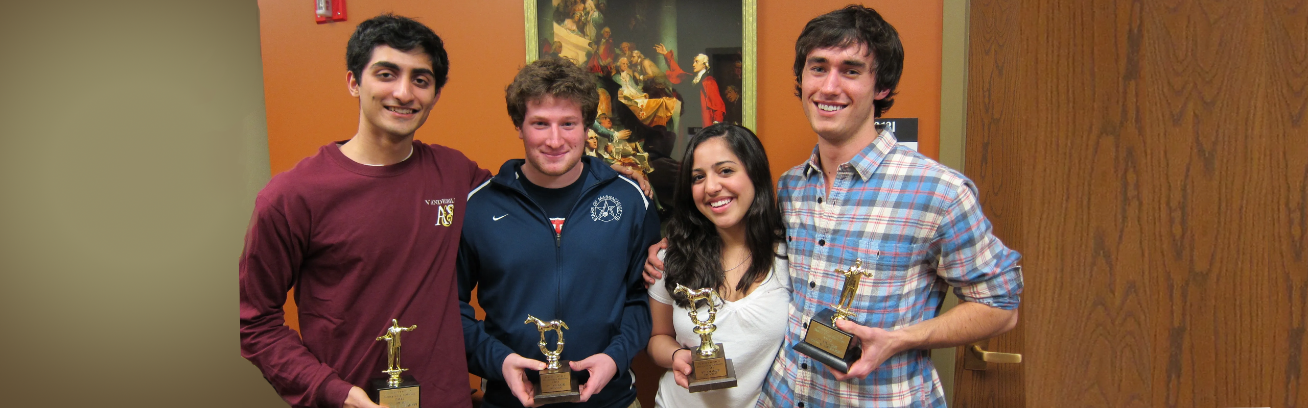 Four debate students holding trophies