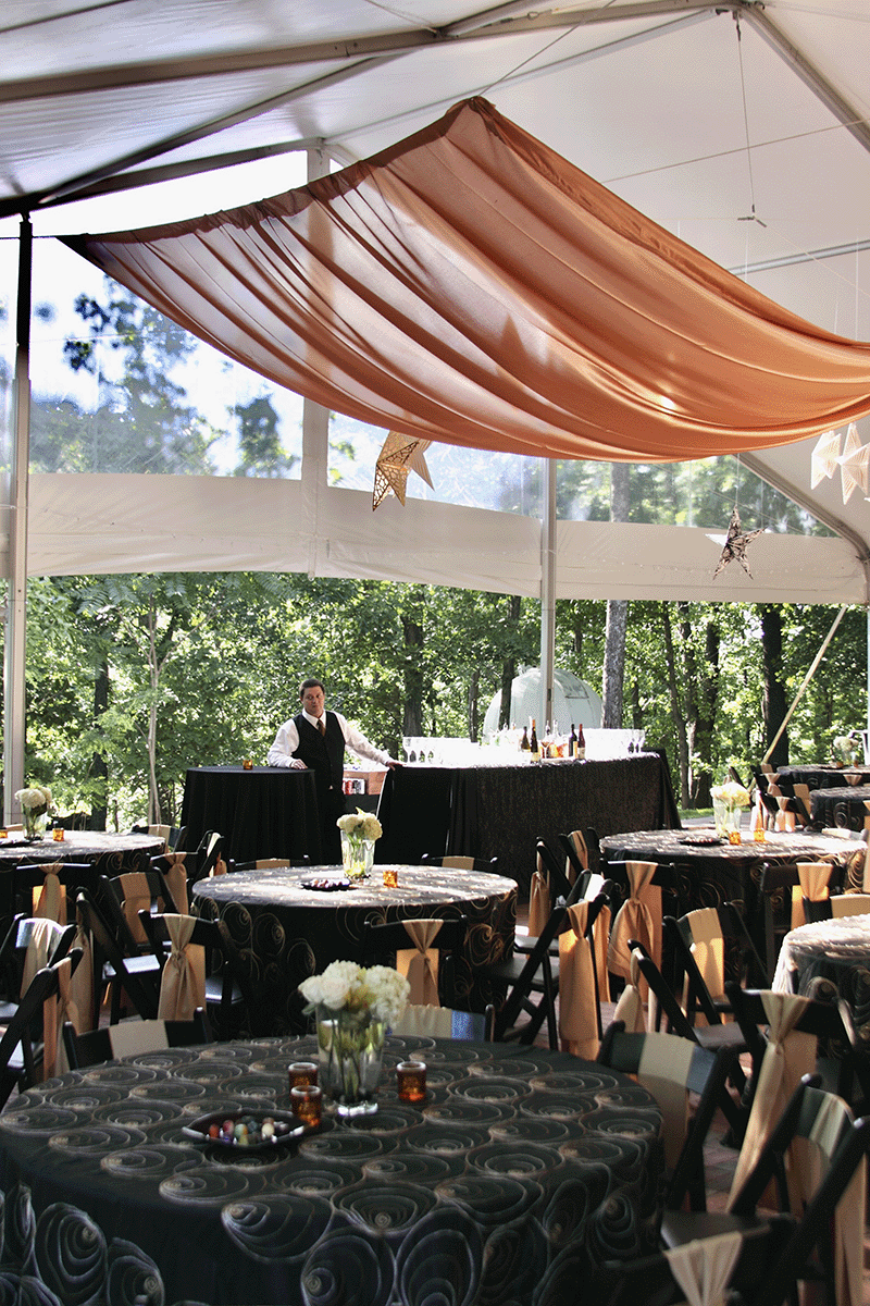 Outdoor event space at Vanderbilt Dyer Observatory with a large tent, round tables, hanging star decorations, and forest backdrop, set for a formal gathering.