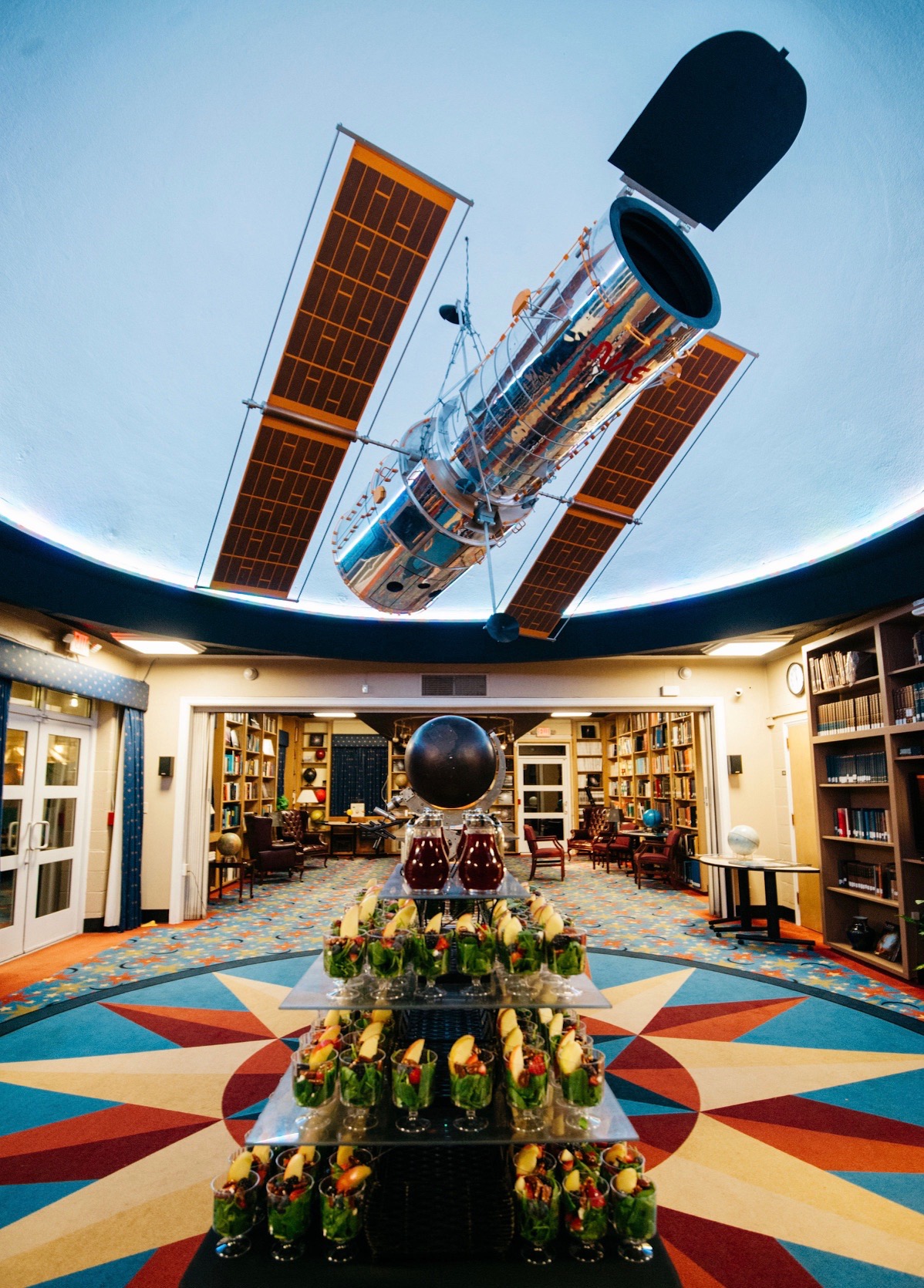 Interior view of Dyer Observatory library during an event, elegant catering setup in foreground, with a view a large model of the Hubble telescope overhead