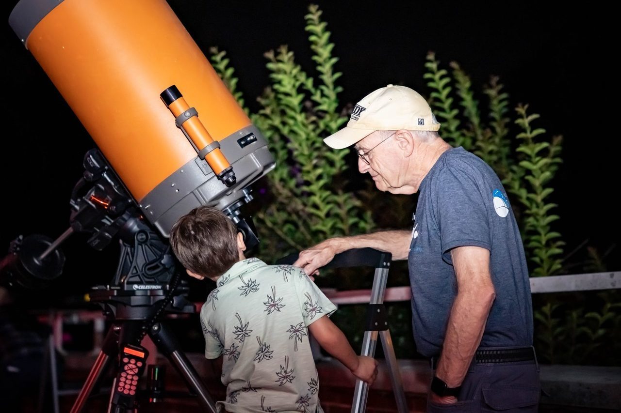 little boy and older man looking at a telescope