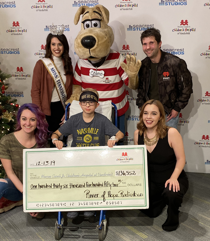 Andrew Whitaker, a patient at Monroe Carell Jr. Children’s Hospital at Vanderbilt, holds the check for the 15th annual River of Hope Radiothon. The Children’s Miracle Network Hospital event raised $136,552 for the hospital. Shown in Seacrest Studio, from left, are Robyn Fomusa, promotions director, Kerri Arnold, Miss Tennessee, Champ, Jonathan Shuford, program director, and Savannah Grimm, on-air host.