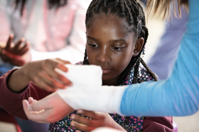 Sydney Meneese, 9, creates a wrap with gauze. (photo by Erin O. Smith)