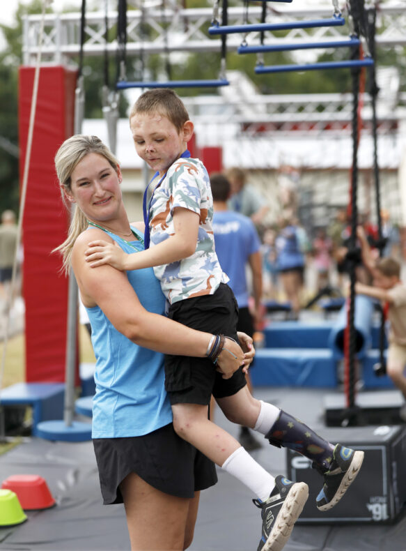 Brittni Davis, Camp Hope director, hoists Brayden Thrasher after he completes the obstacle course. (photo by Donn Jones)