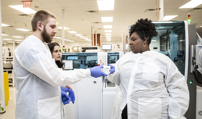 Alexzandria Collins with Specimen Receiving, hands off samples to Zach Mebane, left, and Alex Pagano with the Core Laboratory. (photo by Susan Urmy)