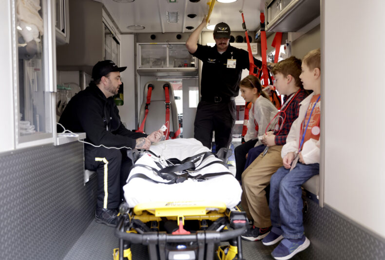 LifeFlight Ground Transport Base staff Justin Weaver, EMT-B, left, and Glen Ridner, AEMT, show young visitors to VUMC EM Family Day around the inside of an ambulance. (photo by Donn Jones) 