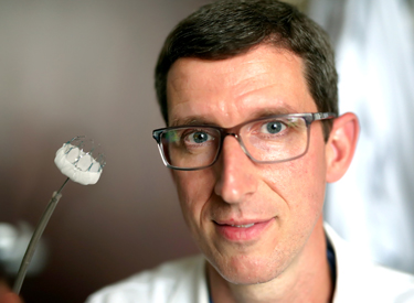Christopher Ellis, M.D., holds up the device available at Vanderbilt to help reduce the risk of stroke in patients with non valvular atrial fibrillation. (photo by Joe Howell)
