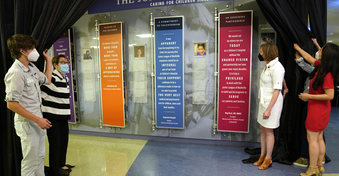 From left, patient ambassador Kael Adams and Meg Rush, MD, join Jenny Barker and Taryn Anderson of the Junior League of Nashville to unveil the new history wall in Children’s Hospital showcasing the Junior League’s extensive support over the past century.