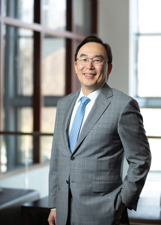 Yu Shyr, PhD, is wearing a gray suit with a blue necktie smiling in a well lit part of the VUMC campus. He is a biostatistician who came to VUMC in 1994.
