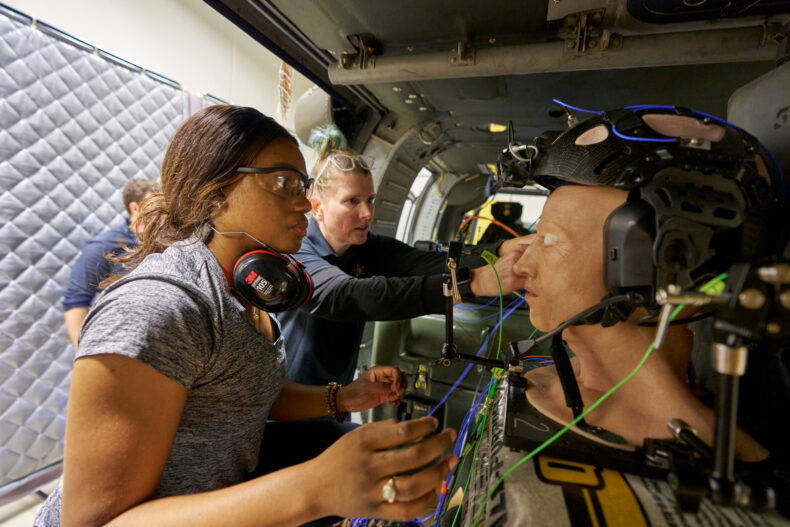 Research assistant Sariah D’Empaire Salomon (front) positions a BIHF, ensuring that all sensors and the helmet are appropriately positioned, while engineer Janette Meyer, PhD, double-checks the sensors and their connections. (photo by Harrison McClary/Vanderbilt University)