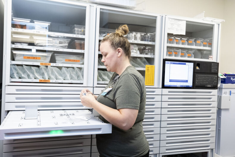 Pharmacy technician Kate Copley fills the sliding drawers with medications and supplies in a secure dispensary. (photo by Susan Urmy)