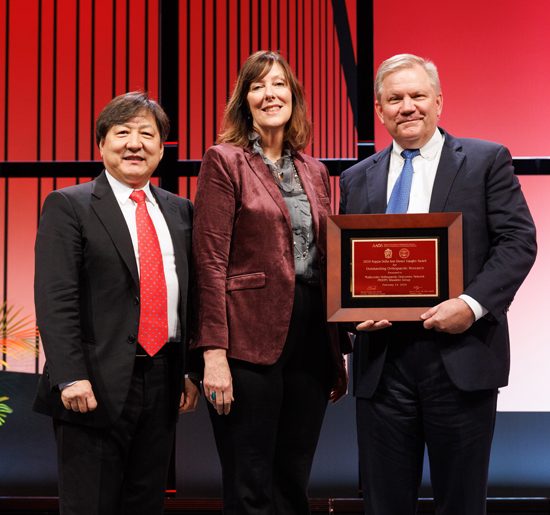 Francis Lee, MD, PhD, MBA, chair of Orthopaedic Research and Education Foundation Grant Committee, left, and Kristen Power of the Kappa Delta Foundation presented John (Jed) Kuhn and the MOON Shoulder Group with the 2024 Kappa Delta Ann Doner Vaughn Award. 