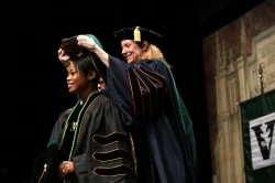 School of Medicine graduate Rivka Ihejirika, left, receives her hood from Amy Fleming, M.D. (photo by Anne Rayner)