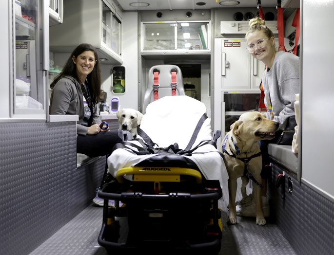 VUMC’s Tiffany Wright, SLP, left, and Retrieving Independence’s Michaela Ping, work with Kai and Mia inside a Vanderbilt LifeFlight ground ambulance. (photo by Donn Jones)