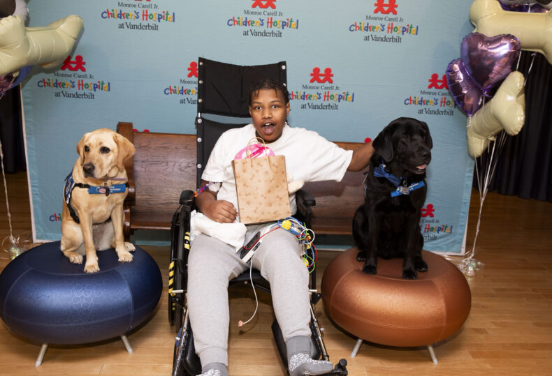 Patient Jeremiah Davis pets Velour, left, and Squid at this week’s event announcing Velour’s arrival as the newest facility dog at Monroe Carell Jr. Children’s Hospital at Vanderbilt. (photo by Susan Urmy)