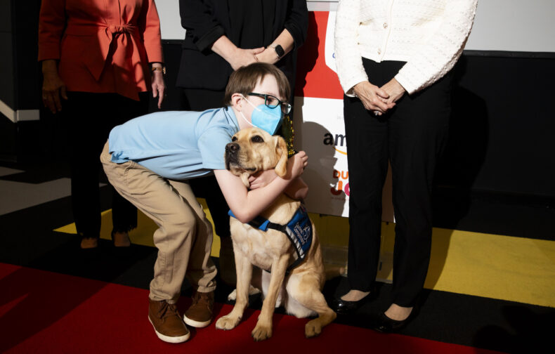 Nico Thompson gives facility dog Velour a hug at this week’s event. (photo by Susan Urmy)