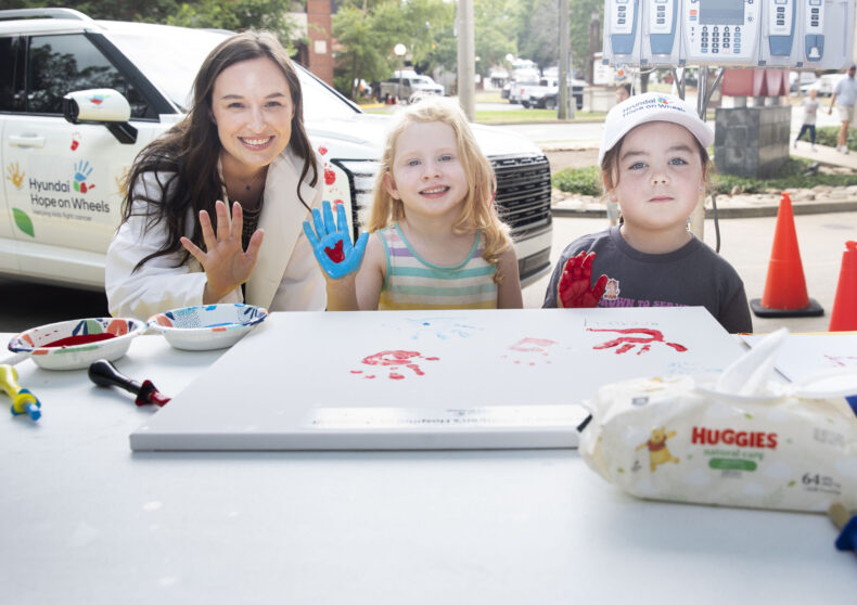 Kaille Meguiar, DO, MPH, left, Greta Ford and Rowan Bailey pose for a photo during the handprint ceremony as part of the Hyundai Hope on Wheels event. (photo by Susan Urmy)