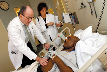 In addition to running a lab, overseeing the IRB, editing a series for the New England Journal of Medicine and jetting off to numerous conferences, Wood, a British-trained clinician, sees patients, like Larry Holbrook, with resident Dr. Jennifer Herrel. (photo by Dana Johnson)