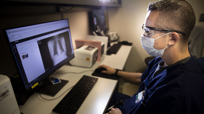 Tyler Barrett, MD, MSCI, reviews an imaging scan in the VUAH Emergency Department, where a dedicated process ensures follow-up of suspicious images unrelated to a patient’s injuries. (photo by Susan Urmy)