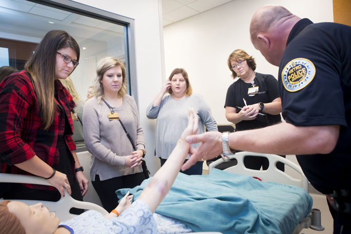 A Metro Nashville Police Department crime scene investigator uses a nursing mannequin with simulated bruising to demonstrate how to photograph assault injuries to VUSN students Erin Talbott, left, Lauren Lariscy, Jennifer Pricher and Rita Peters.