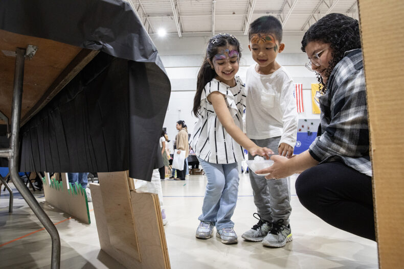 Saanvi Thapa, 5, and Asim Dura, 6, play a game with postdoctoral fellow Valeria Reyes Ruiz, PhD. (photo by Erin O. Smith)