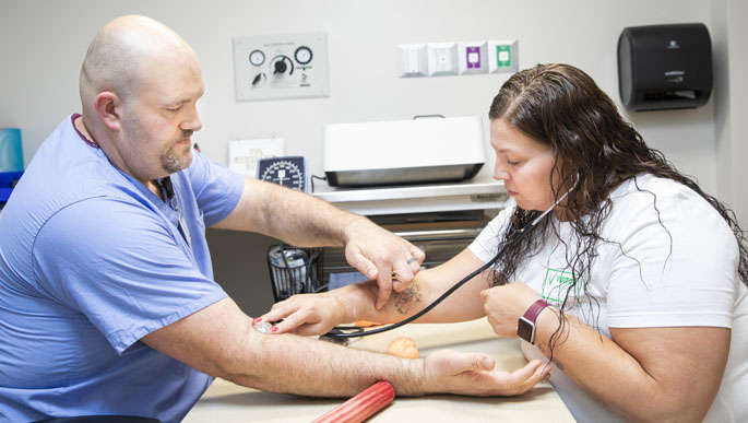 Justin Stehr, OTR, CHT, an occupational therapist with the Department of Plastic Surgery’s Division of Hand and Upper Extremity, works with Dawn Reed on neuromuscular re-education of her wrist extensors and grip strength. (photo Susan Urmy)