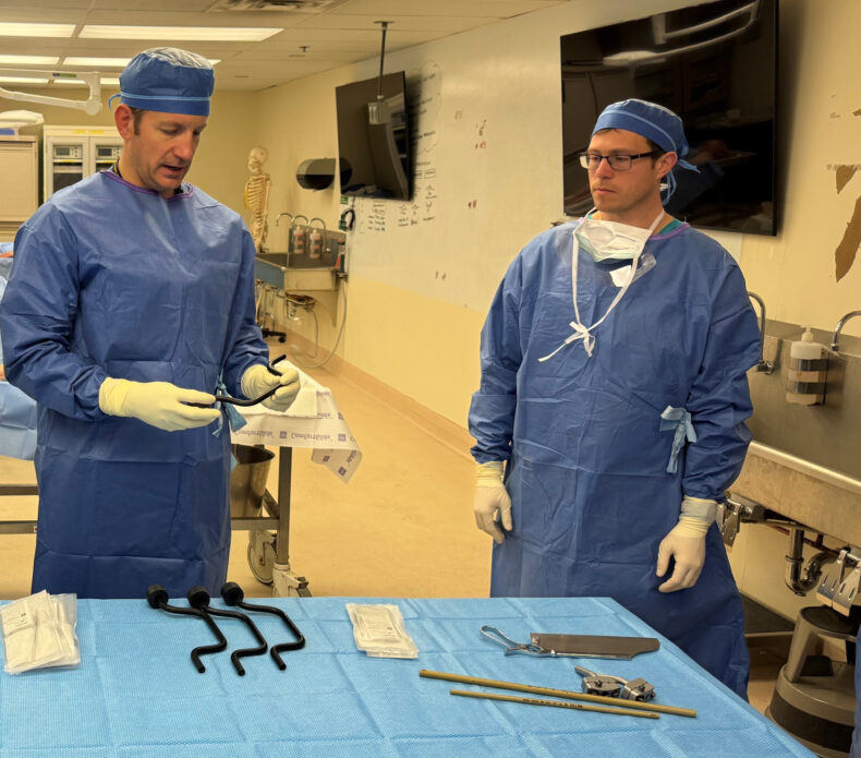 Col. Daniel Stinner, MD, PhD, associate professor of Orthopaedic Surgery, left, explains the instruments required to apply an external fixator to stabilize a severe extremity injury in an austere environment. 