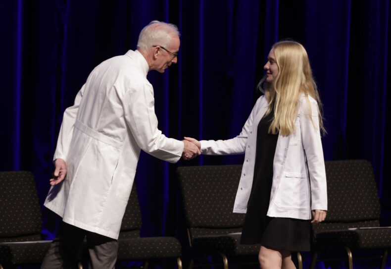 Lily Bensen of St. Paul, Minnesota, is congratulated by Donald Bradley, MD, during the White Coat Ceremony. (photo by Donn Jones)