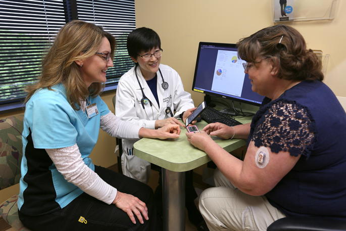 Shichun Bao, MD, PhD, center, and Brenda Weedman, RN, BSN, discuss continuous glucose monitors with patient Sherry Neergaard.