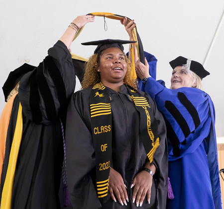 Morgan Perkins receives her hood from Terri Allison, DNP, and Mavis Schorn, PhD.