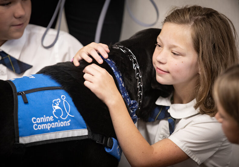 Patient Niah Carver hugs facility dog Squid. (photo by Erin O. Smith)