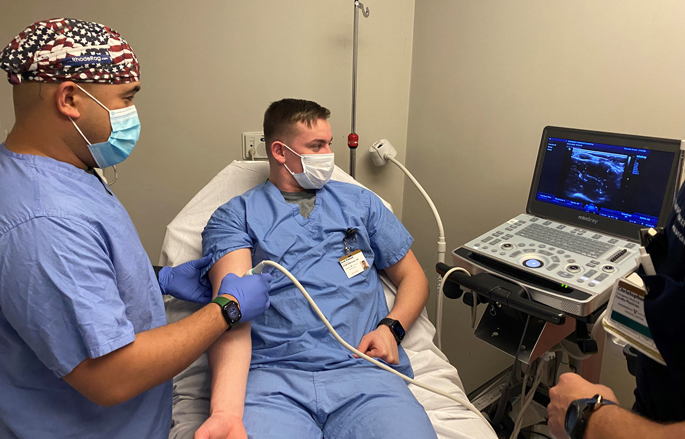 Past SMART participants Army LPN Sgt. Josiah Cubol, left, and Army LPN Spc. Jacob Pritchard, practice ultrasound techniques with Army Military-Civilian Trauma Training Team Emergency Medicine physician Maj. Christopher Bickett, MD. 