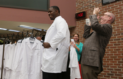David Taylor, from Texas, left, a new graduate student in the Interdisciplinary Graduate Program, smiles after receiving his coat from Marnett. (photo by Anne Rayner)